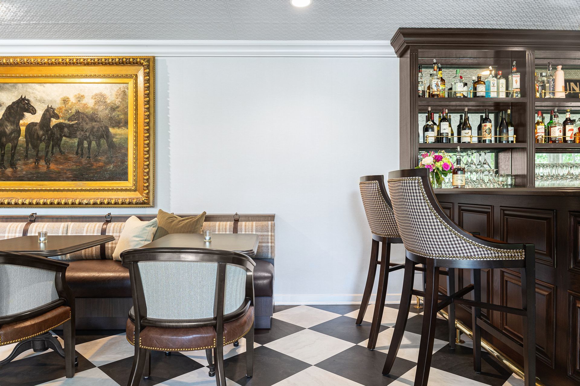 Bar interior with black and white checkered floor, dark wood bar, artwork, and seating.
