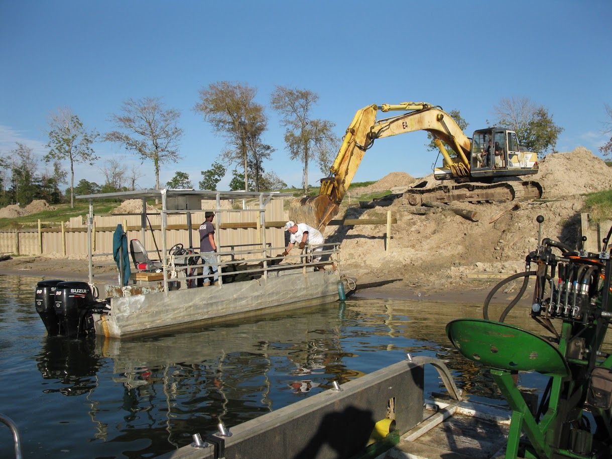 Yellow excavator loading dirt into a large dump truck at a construction site under a blue sky