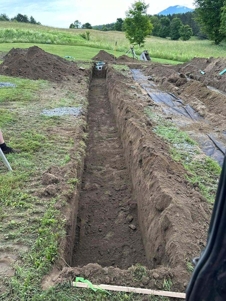 A person is digging a trench in the dirt in a field.
