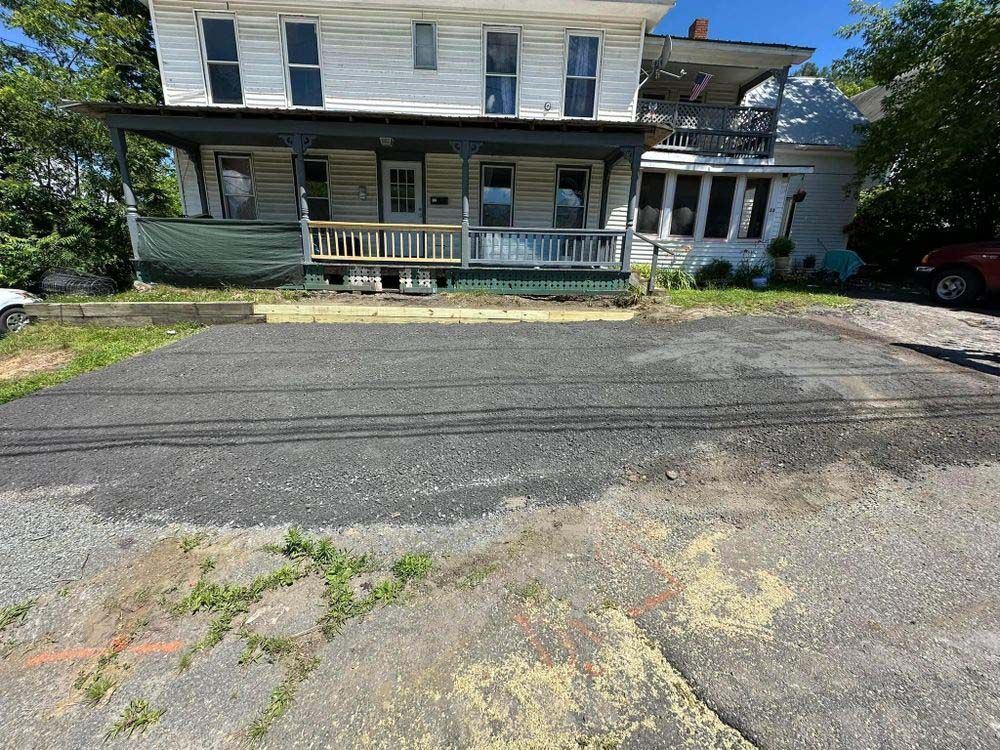A white house with a porch and a car parked in front of it.