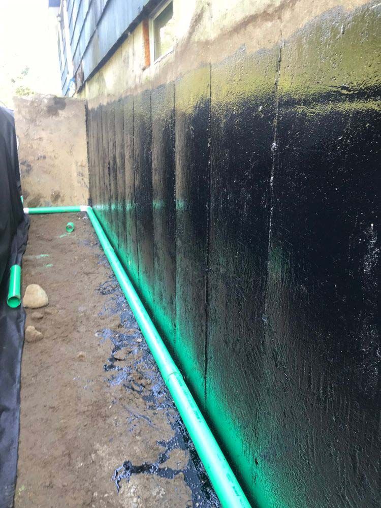 A black wall with green pipes coming out of it.