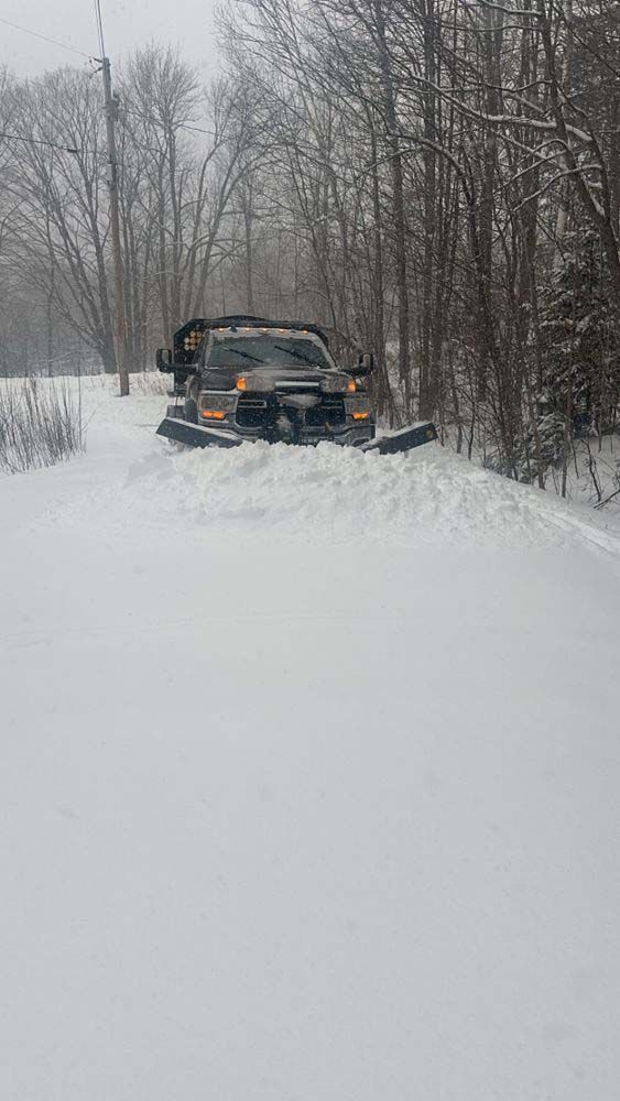 A snow plow is driving down a snow covered road.