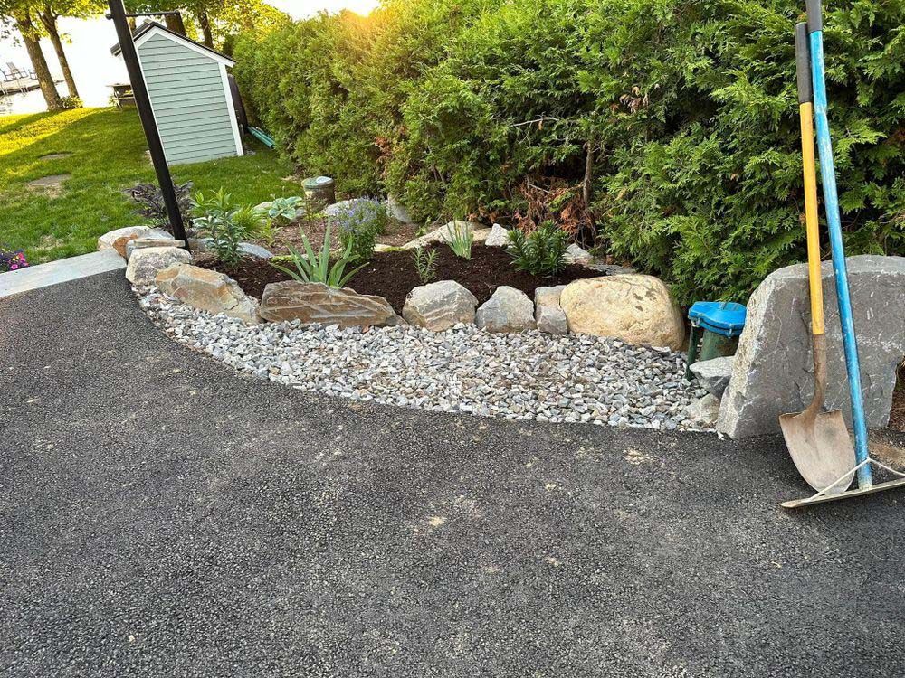 A shovel and rake are sitting on the ground next to a rock garden.
