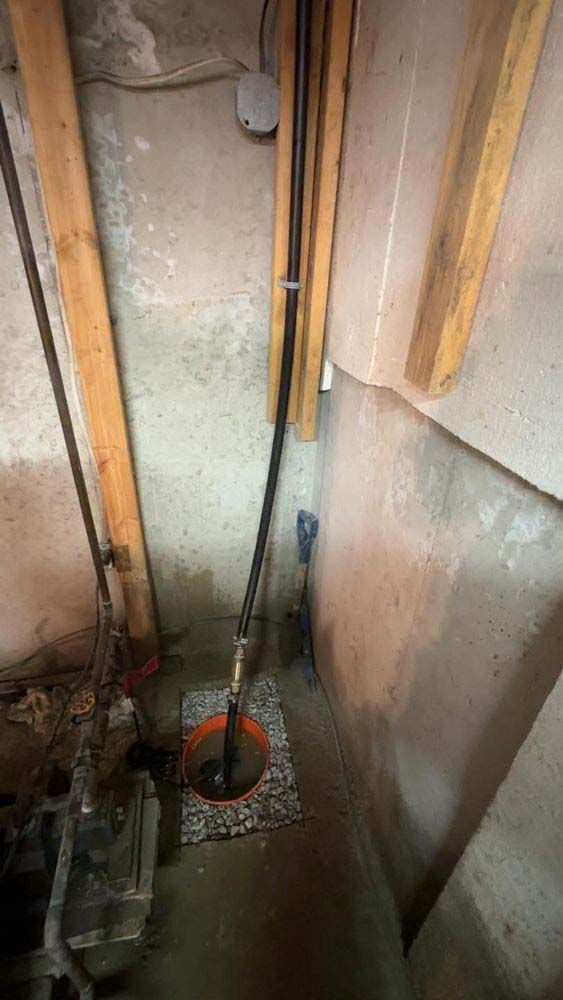 A drain in a basement with a hose attached to it.