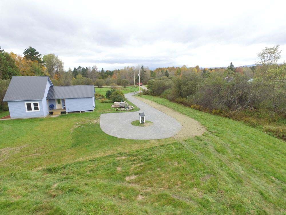 An aerial view of a house in the middle of a grassy field.