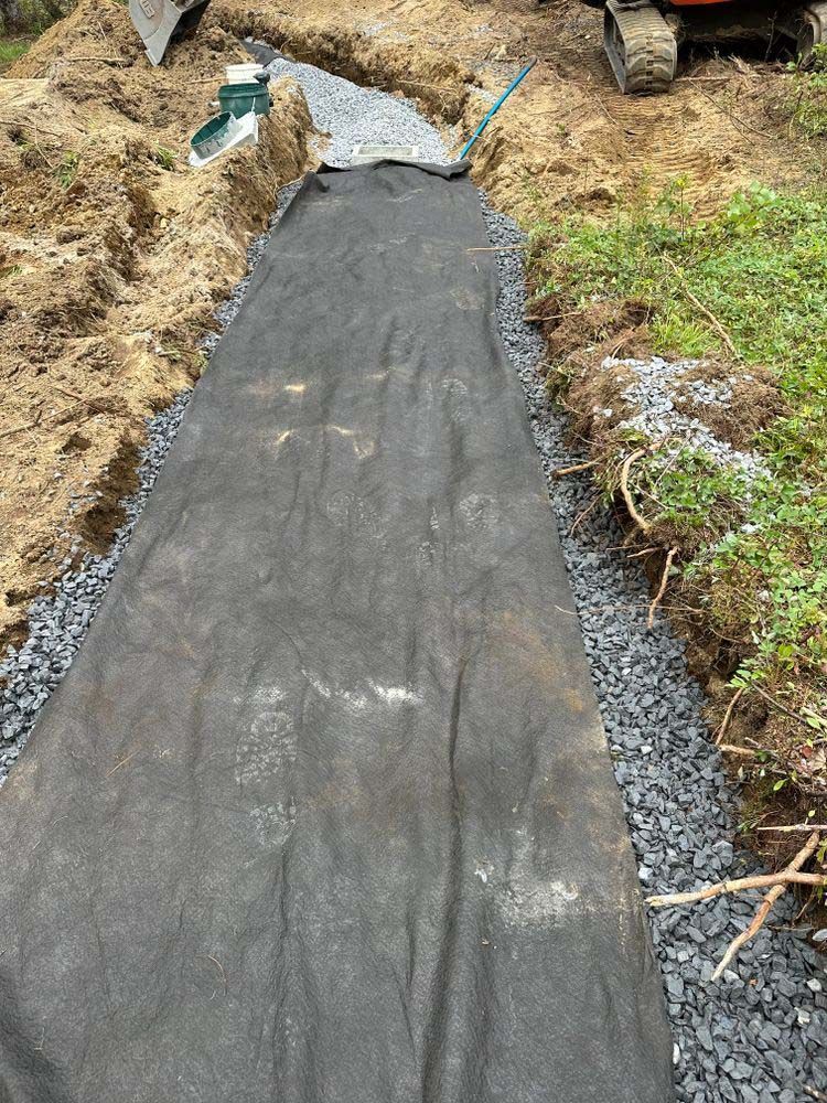 A black tarp is laying on top of a dirt path.