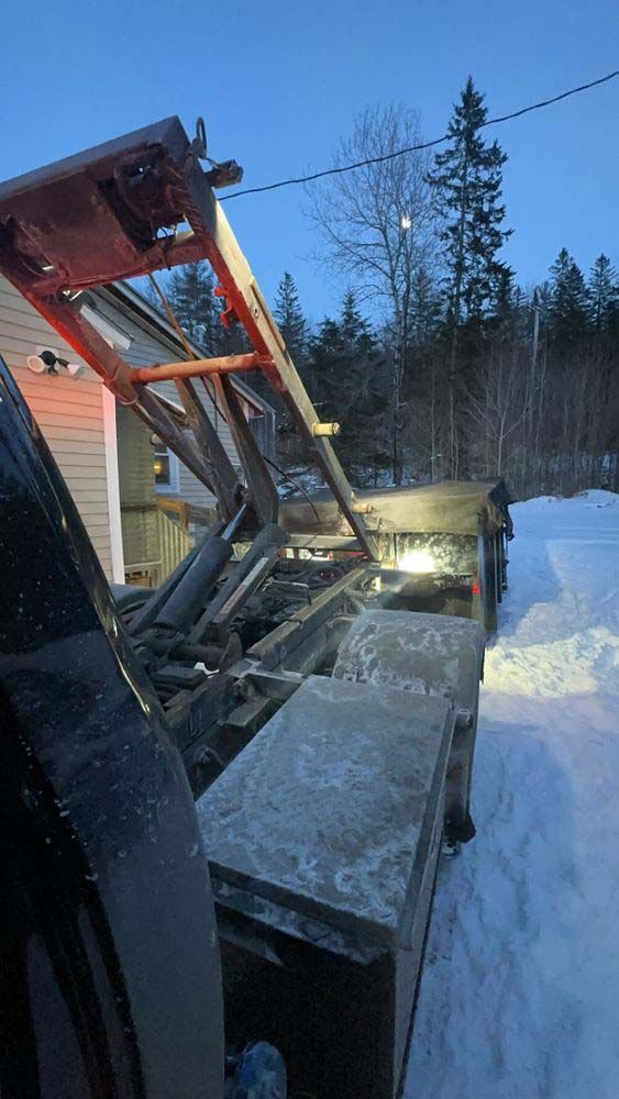 A tow truck is parked in the snow in front of a house.