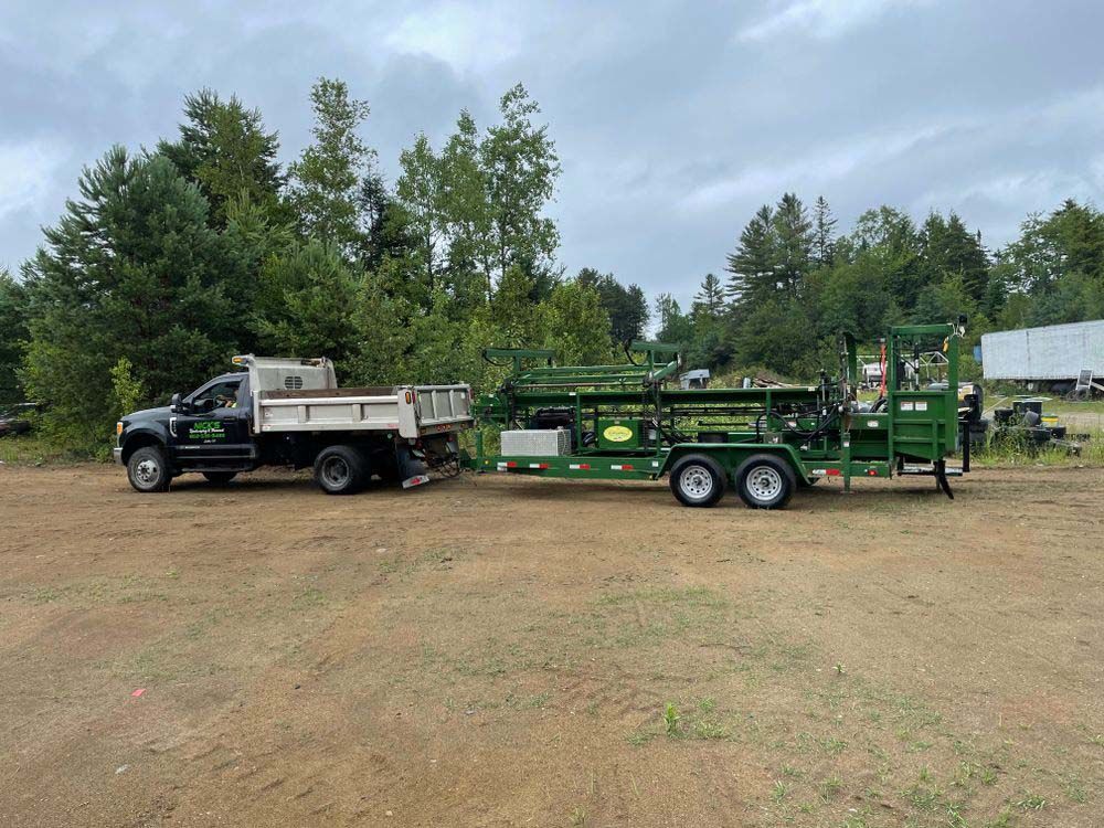 A dump truck and a trailer are parked in a dirt field.