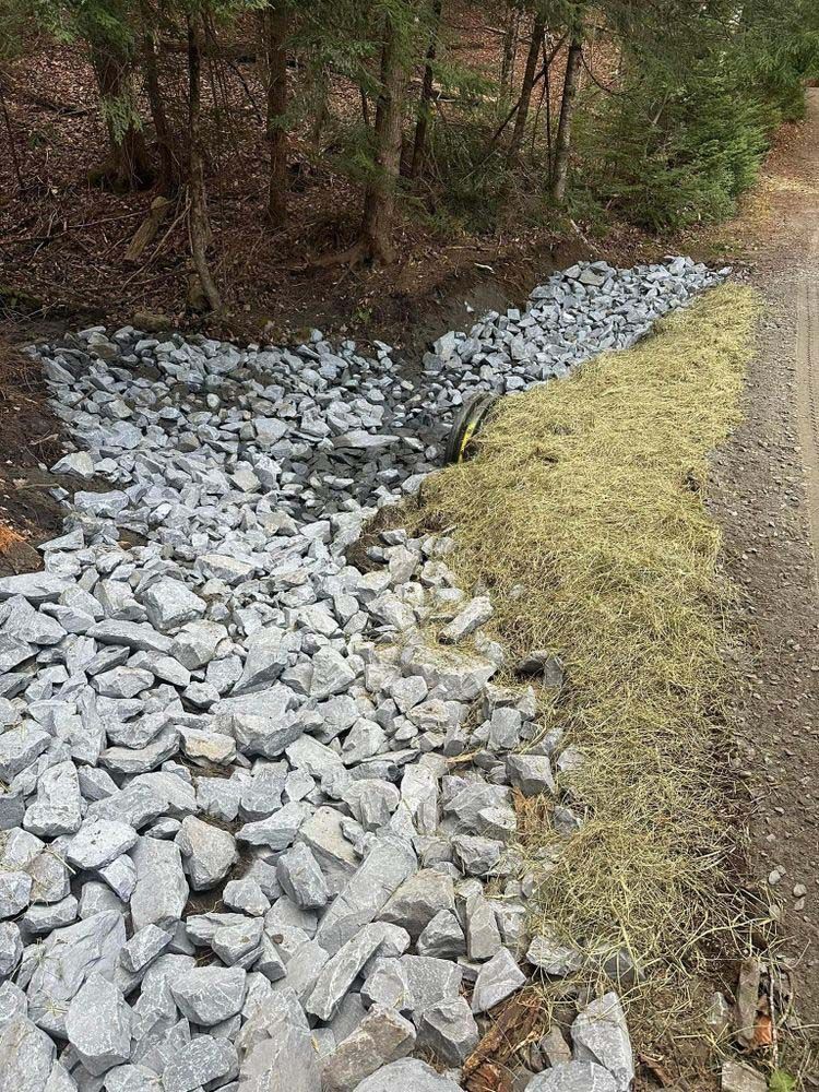 A pile of rocks and hay on the side of a dirt road.