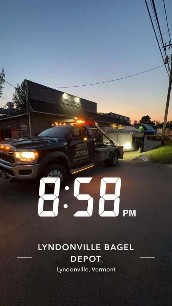 A tow truck is parked on the side of the road in front of a building.