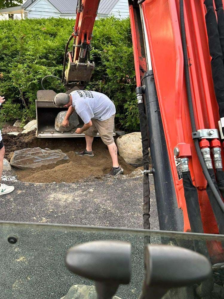 A man is standing next to a large orange excavator.