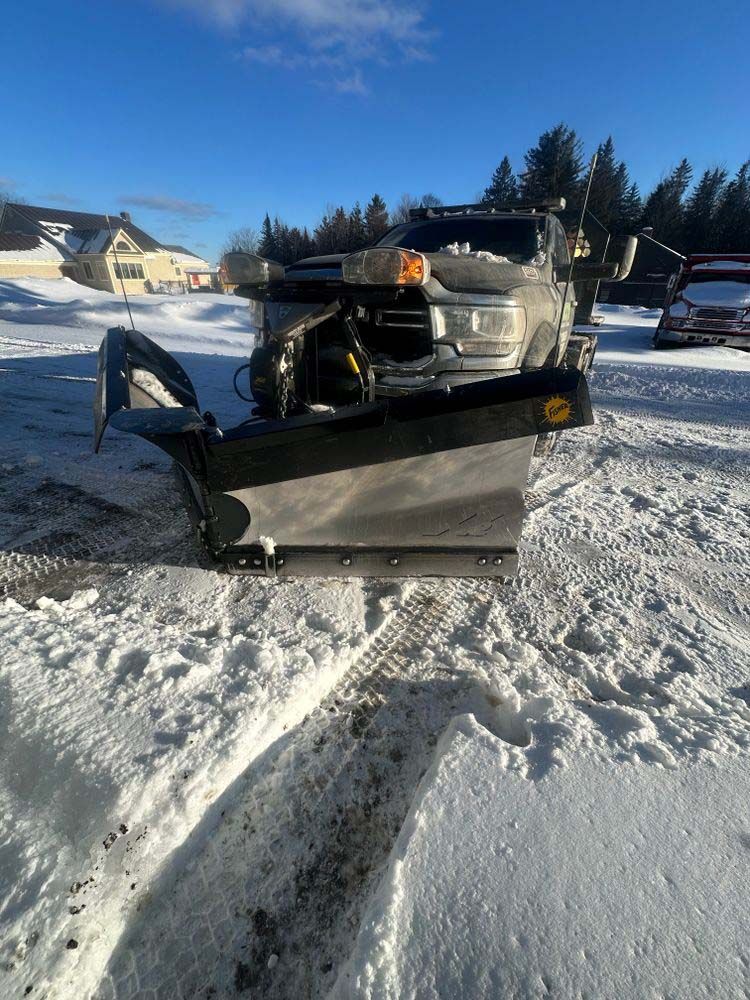 A truck with a snow plow attached to it is parked in the snow.