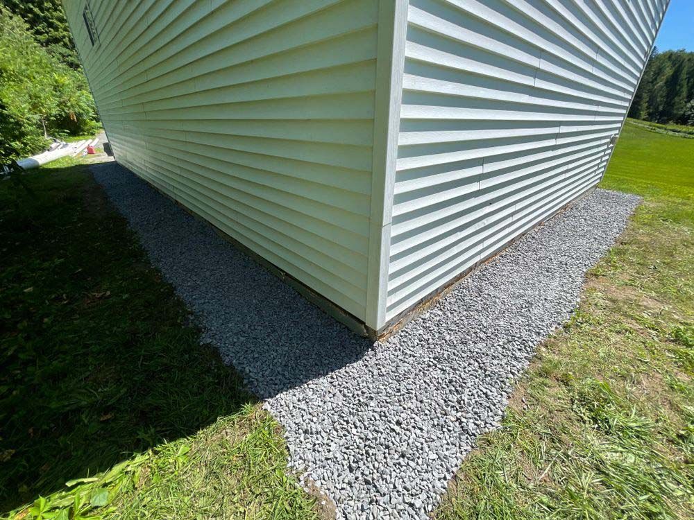 A white house with gravel on the side of it.