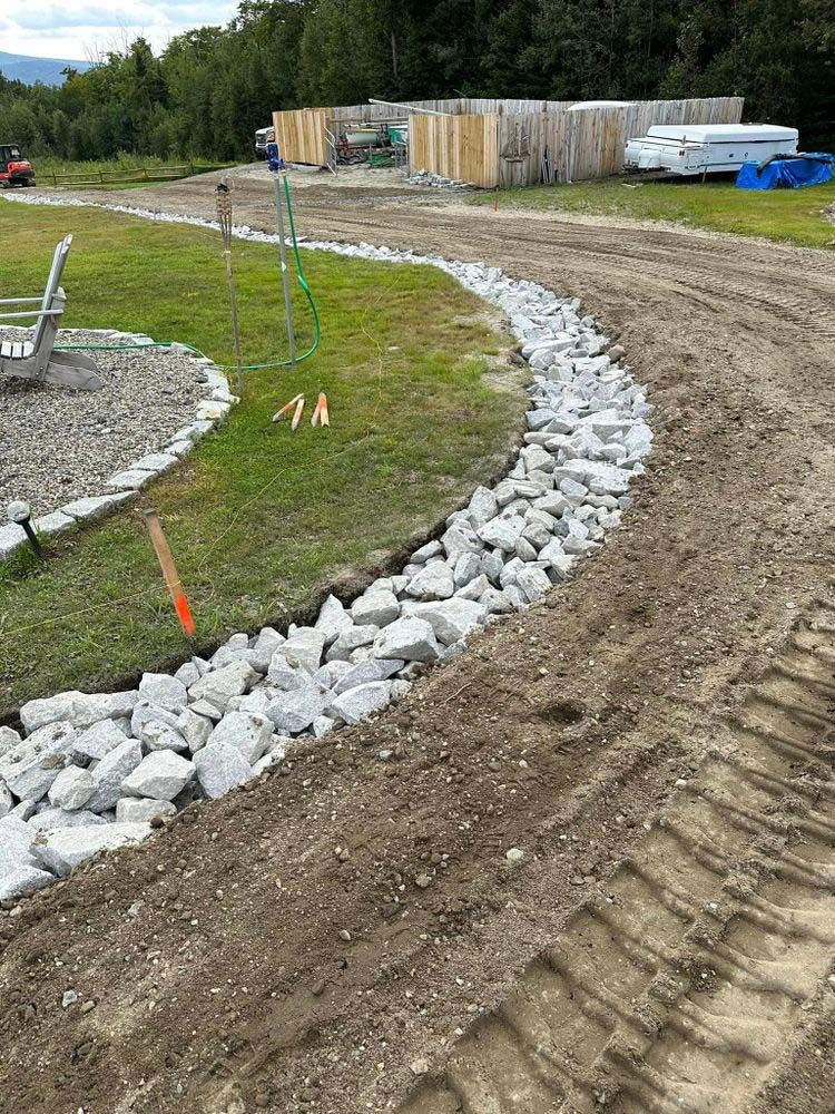 A dirt road with a row of rocks on the side of it.
