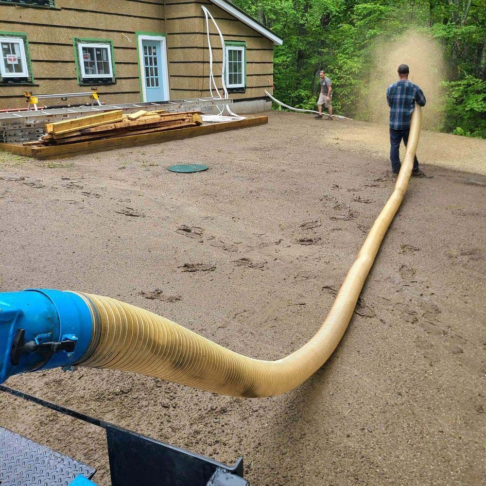 A man is standing in front of a house holding a hose