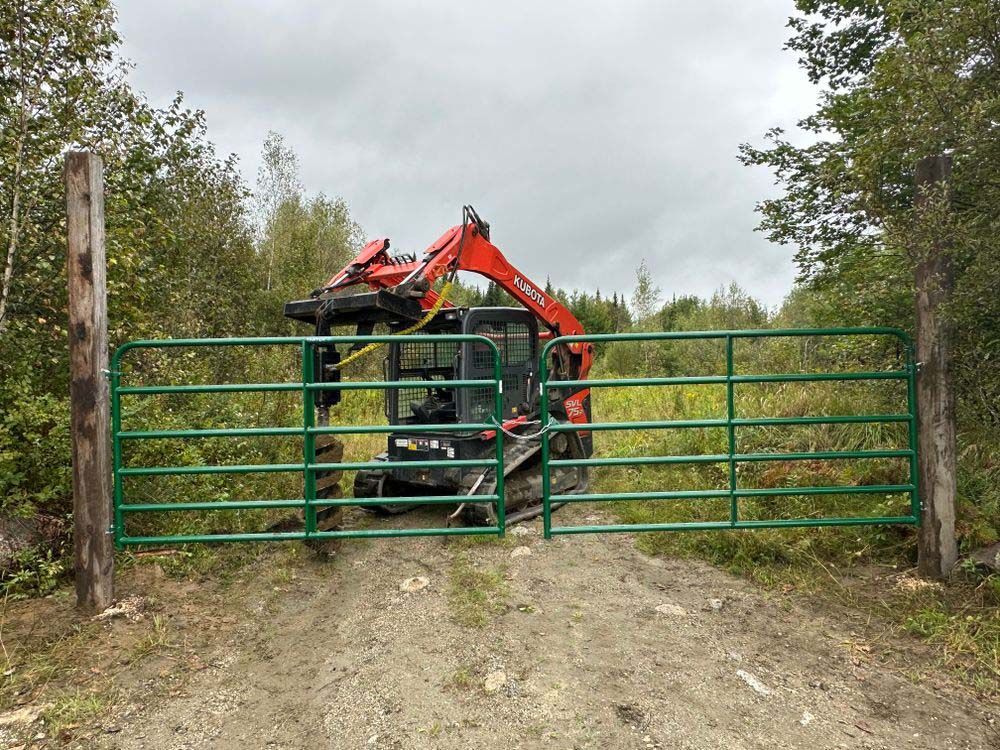 A bulldozer is driving through a gate on a dirt road.