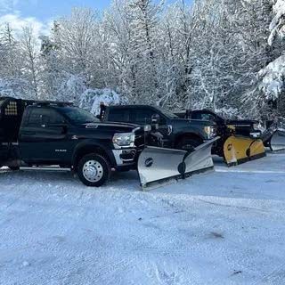 Two snow plows are parked next to each other in the snow.