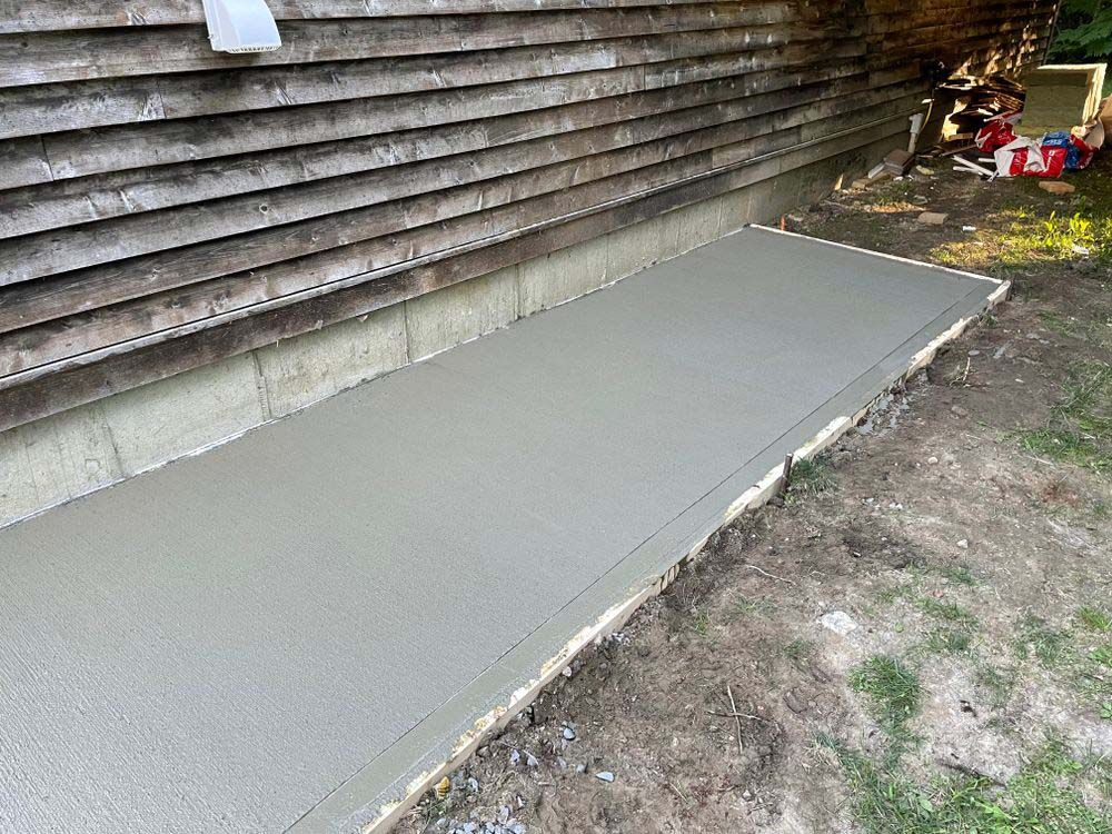 A concrete walkway is being built in front of a wooden building.