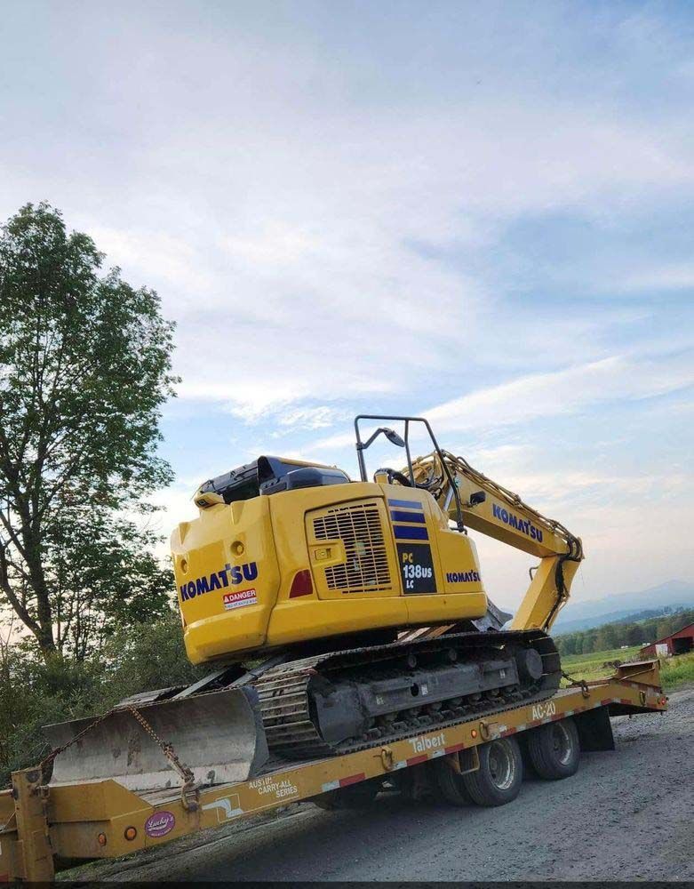 A yellow excavator is sitting on top of a trailer.