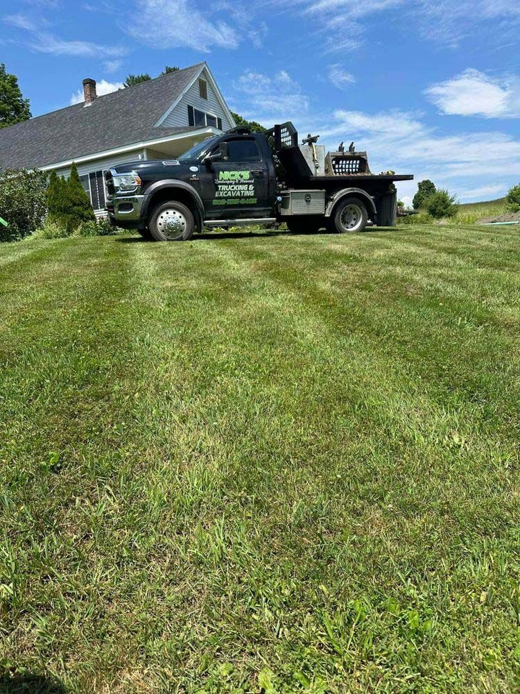 A tow truck is parked in the grass in front of a house.