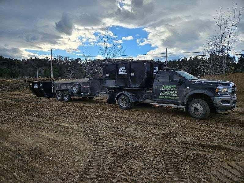 A dump truck is pulling a trailer in a dirt field.