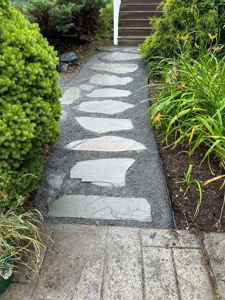 A stone walkway leading to a set of stairs in a garden.