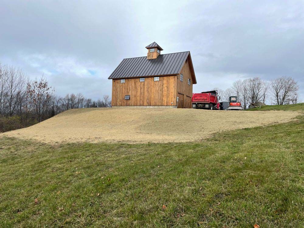 A barn is sitting on top of a grass covered hill.