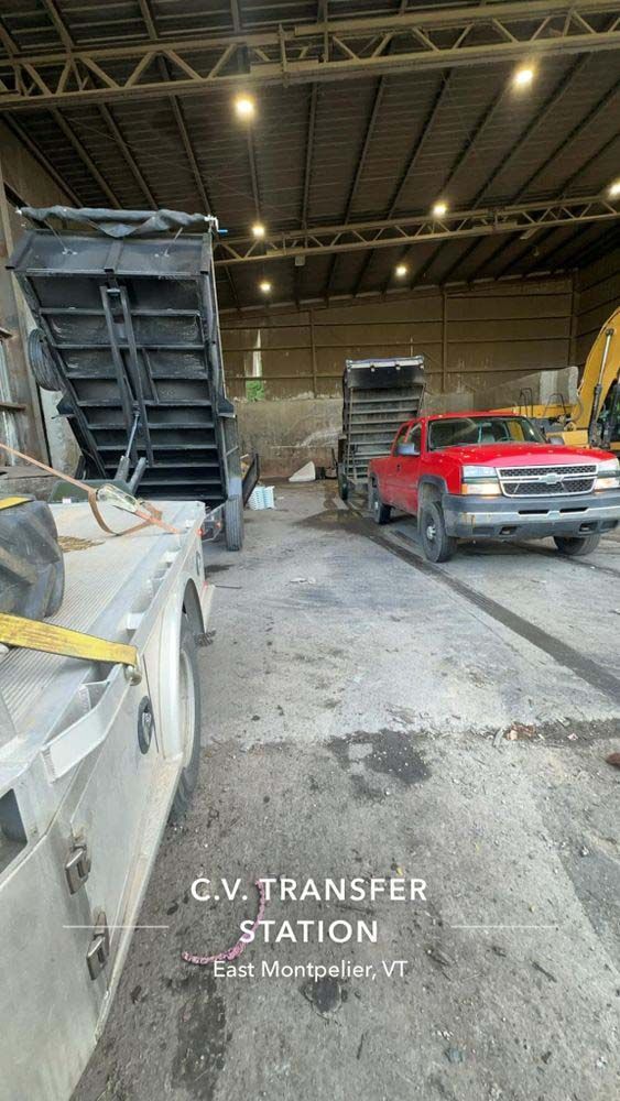 A red truck is being loaded with gravel in a warehouse.