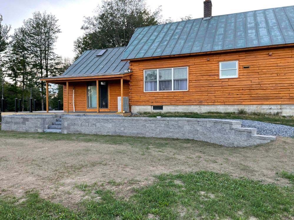 A large wooden house with a metal roof is sitting on top of a lush green field.