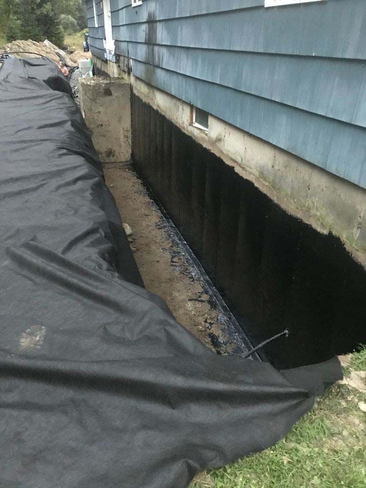 A black tarp is covering a hole in the side of a house.