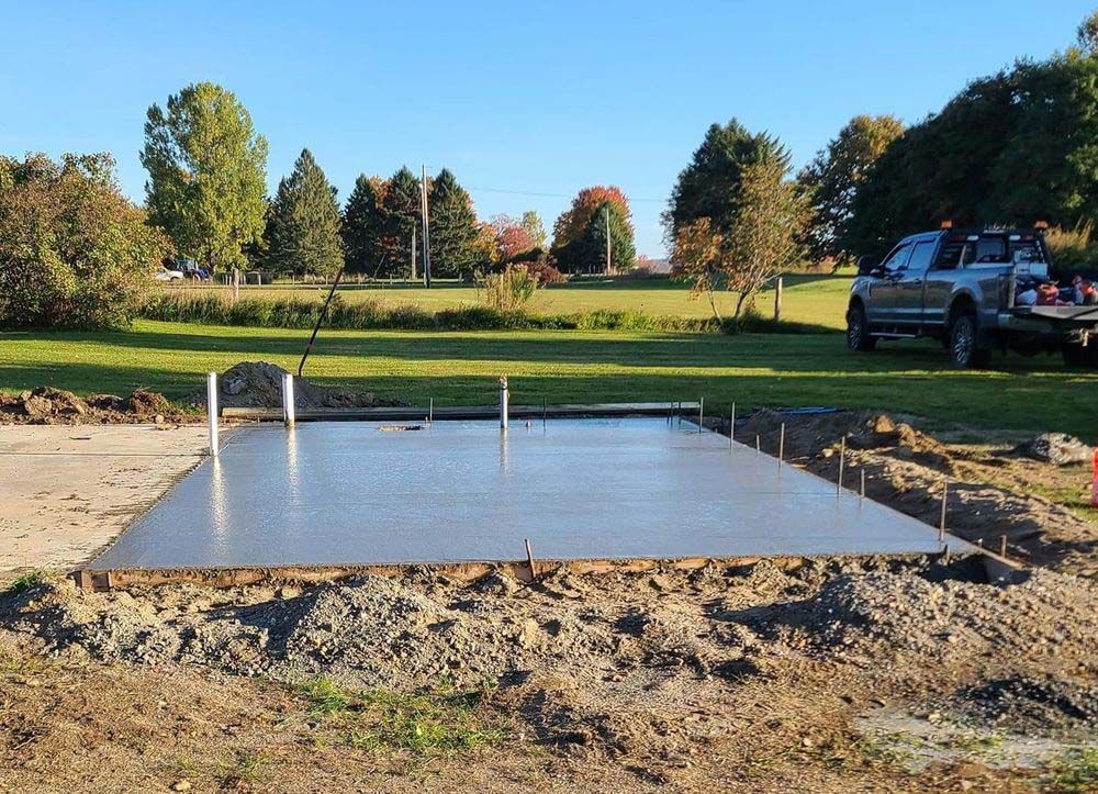 A truck is parked next to a concrete slab in a field