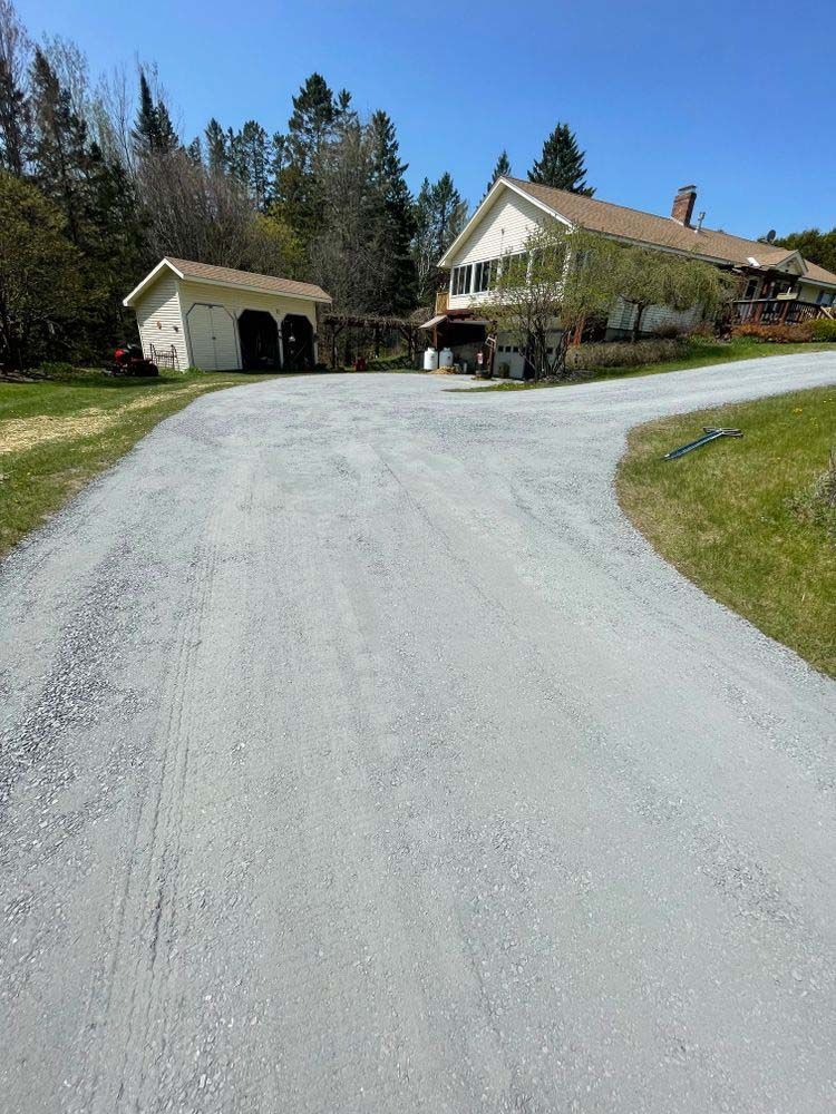 A dirt road leading to a large house with a garage.