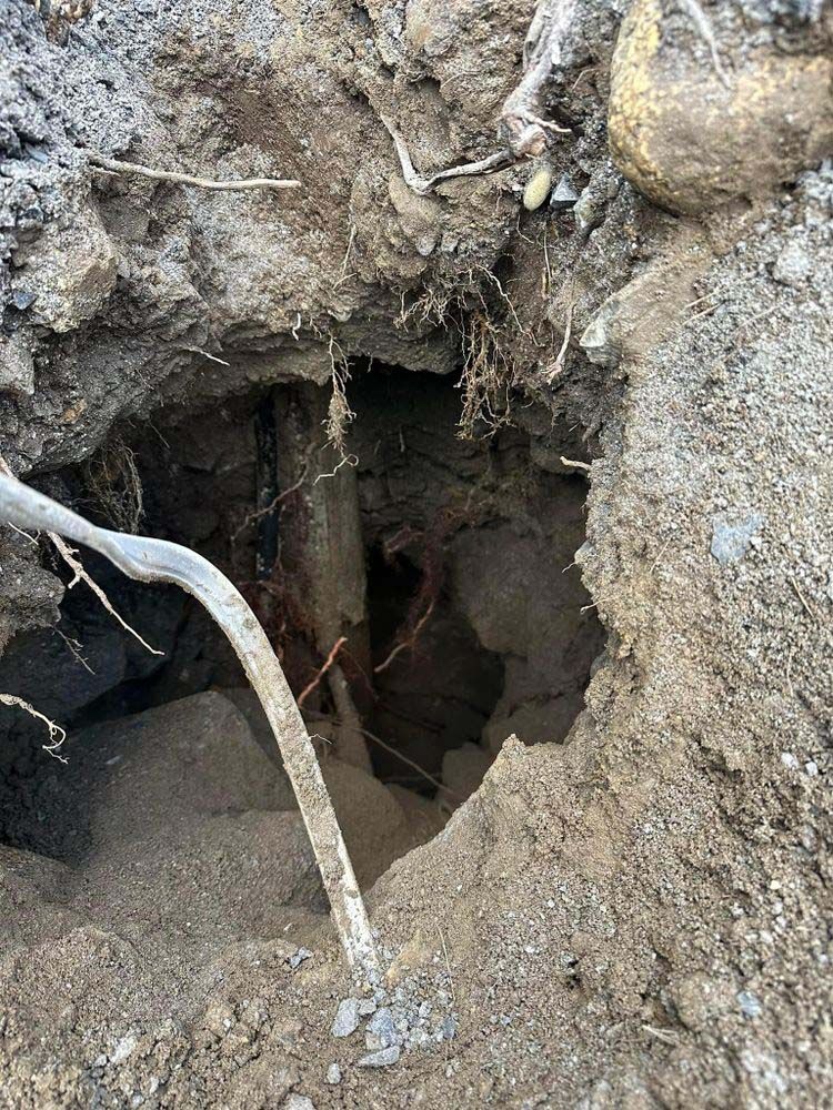 A hole in the ground with a tree branch sticking out of it.