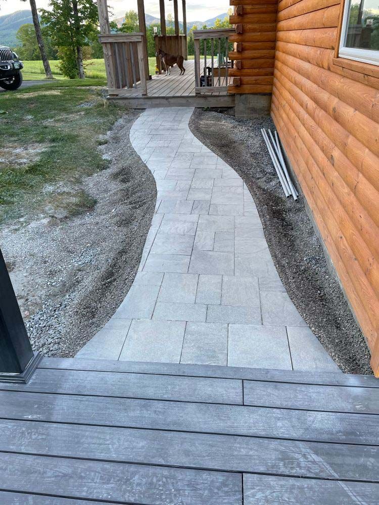 A stone walkway leading to a log cabin.