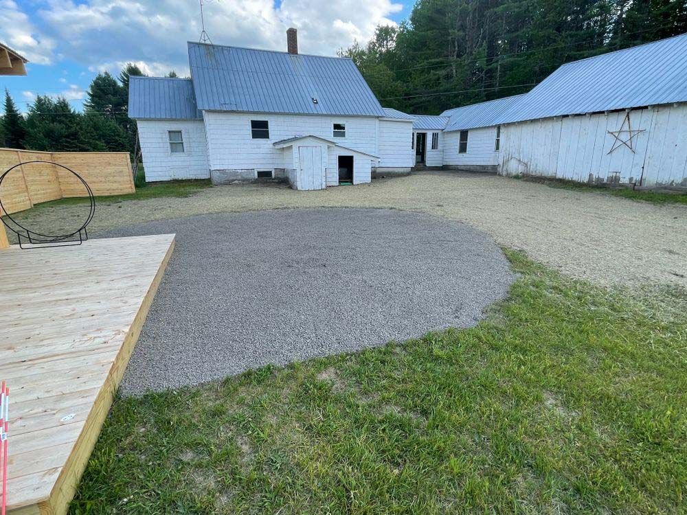 A large white house with a gravel driveway in front of it.