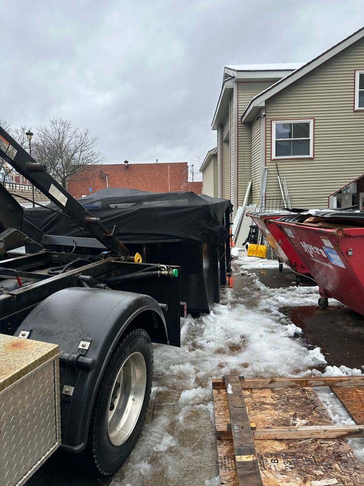 A dump truck is parked in front of a house in the snow.