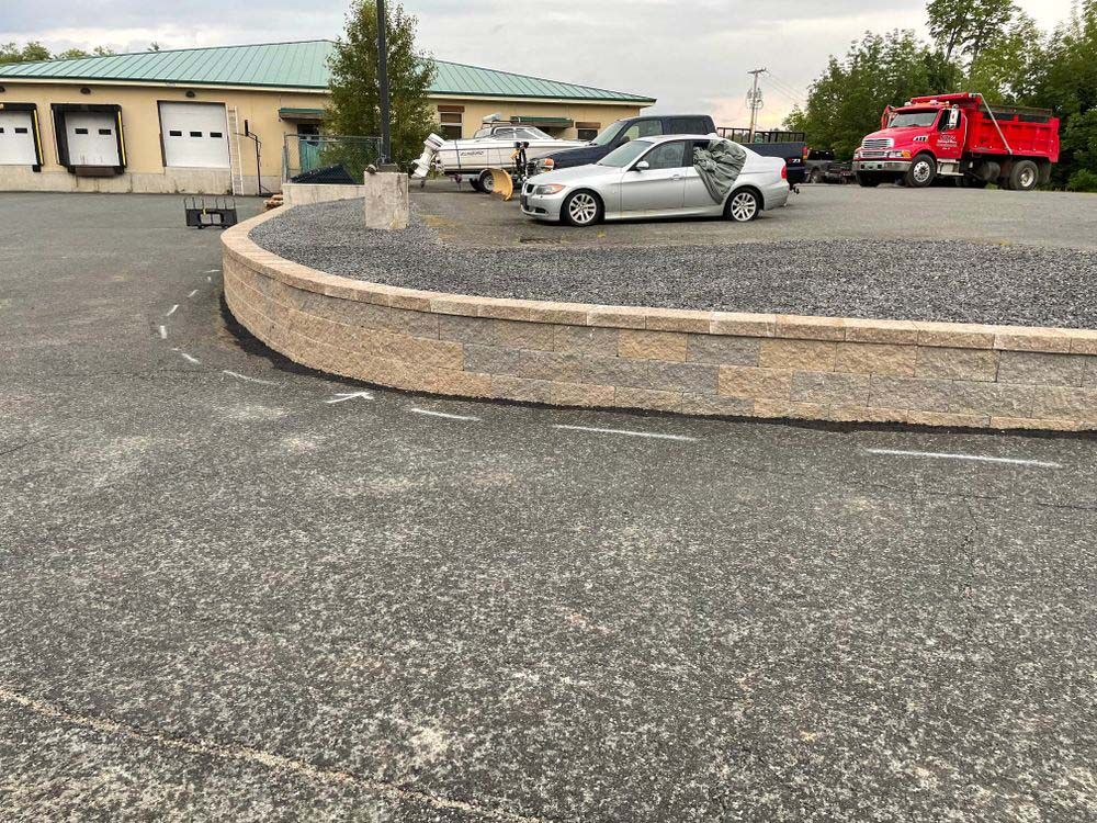 A silver car is parked in a parking lot next to a red truck.