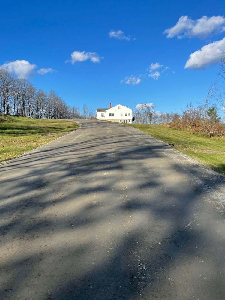 A road with a white house on the side of it.