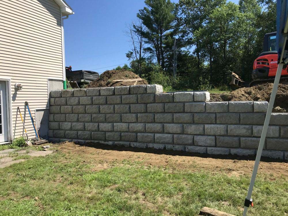 A brick wall is being built in the backyard of a house.