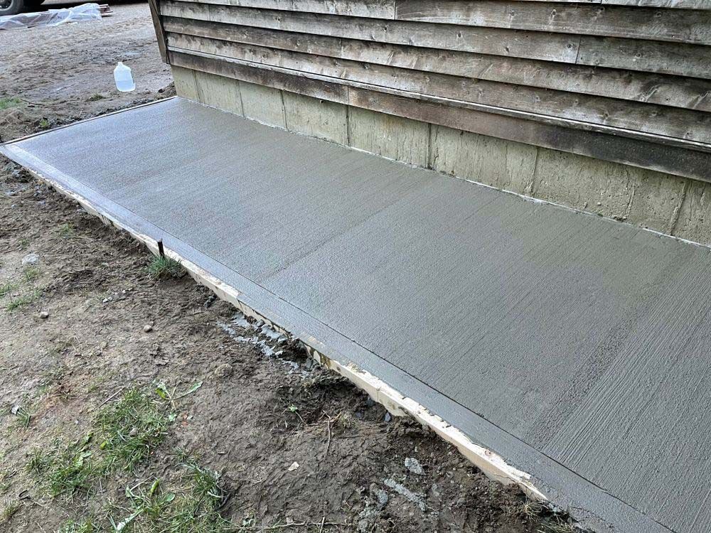 A concrete walkway is being built in front of a house.