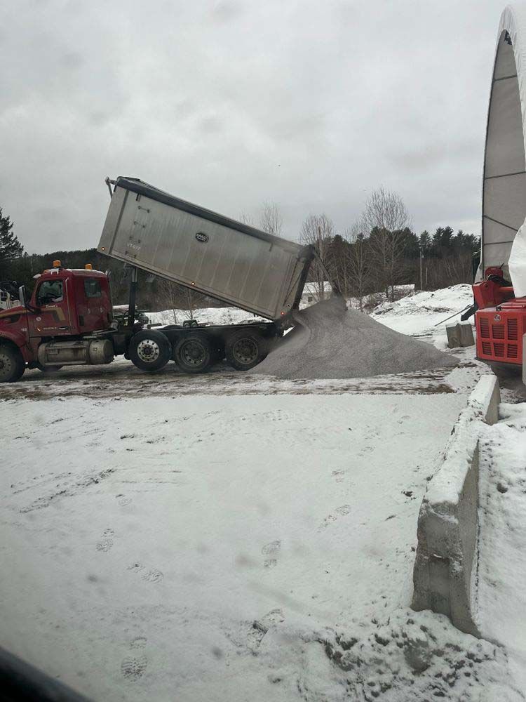 A dump truck is being loaded with snow on a snowy road.