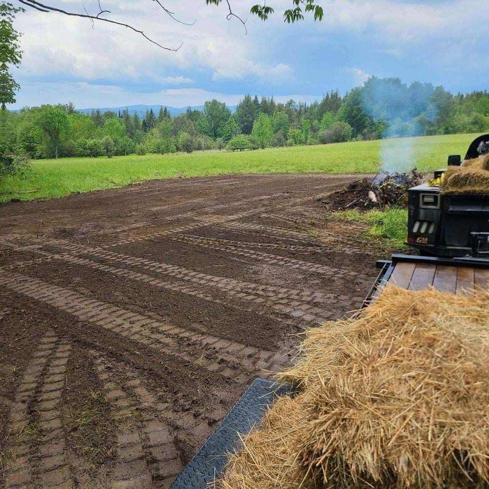 A pile of hay is sitting on the back of a truck in a field.