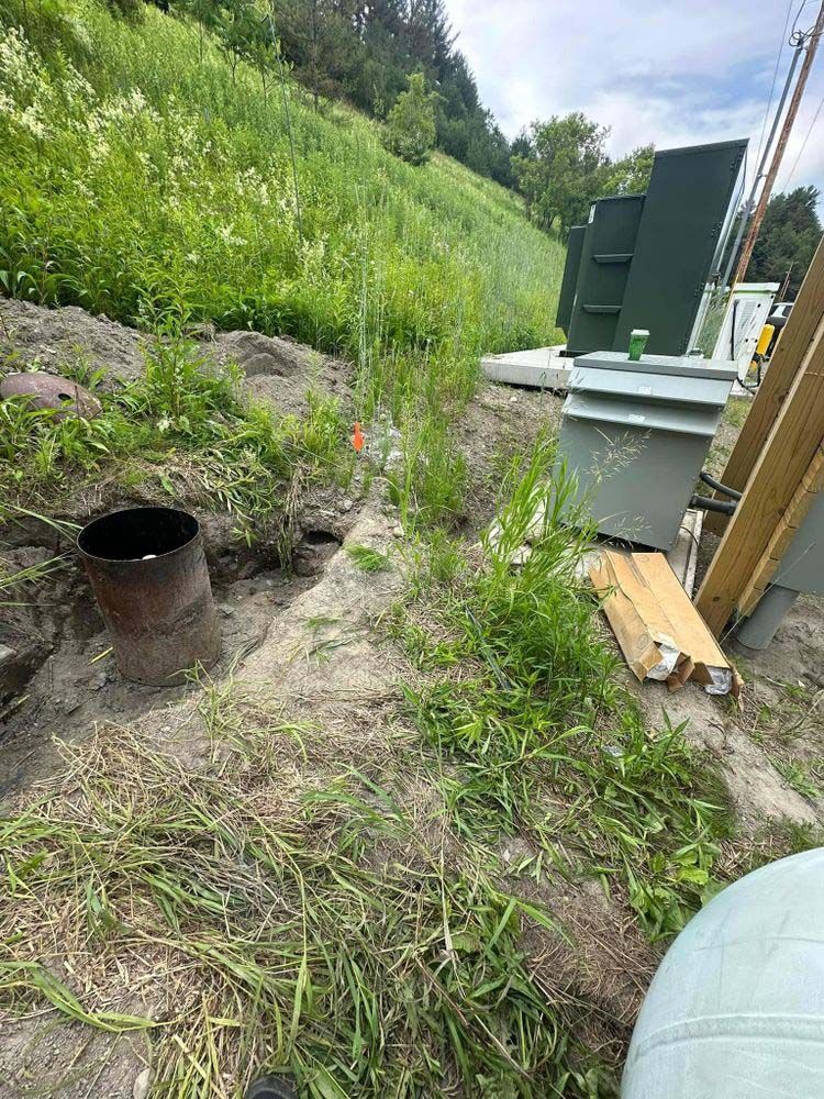 A barrel is sitting in the middle of a dirt field.
