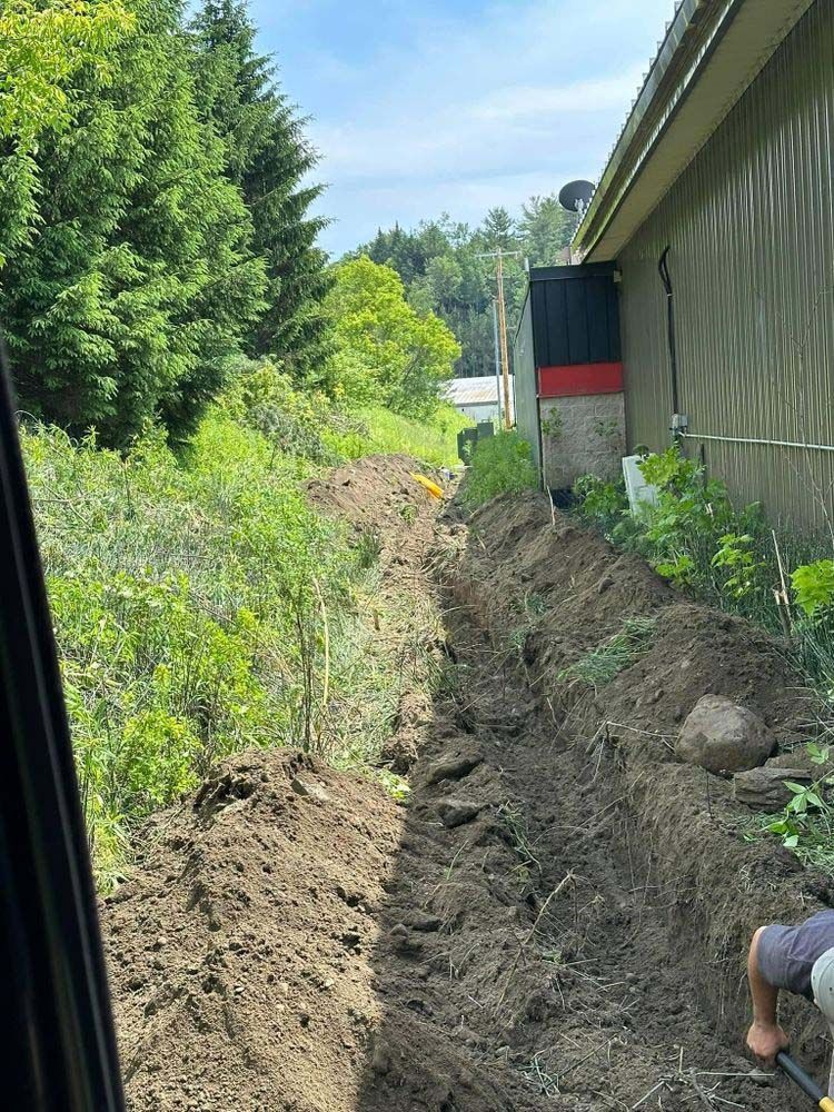 A man is digging a hole in the dirt in front of a building.