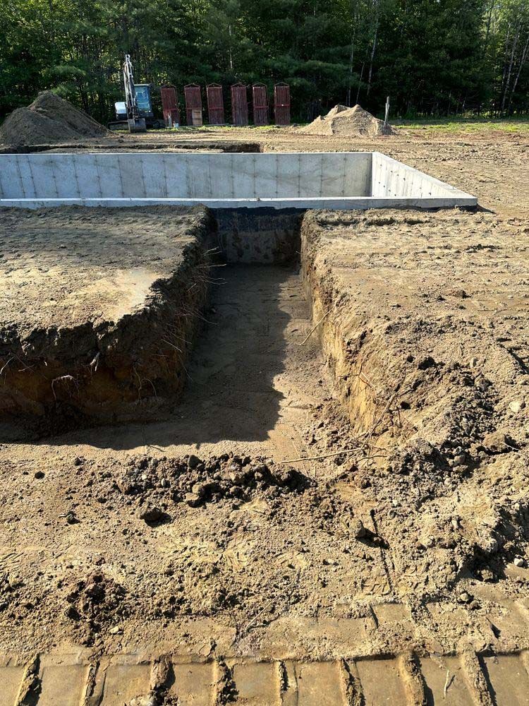 A concrete foundation is being built in a dirt field.
