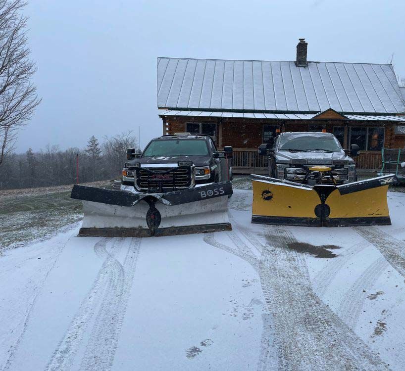 Two snow plows are parked in front of a house.