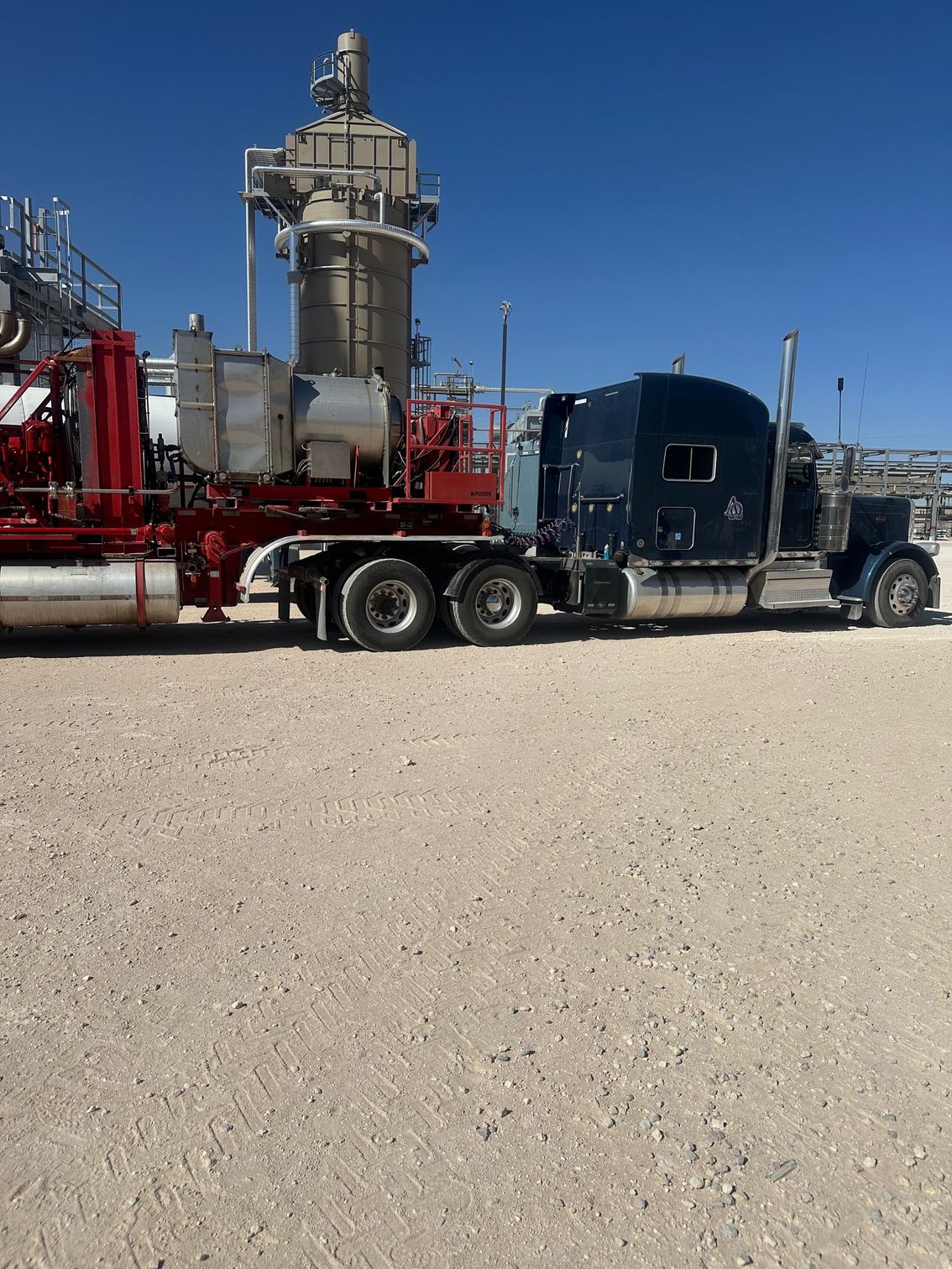 A black semi truck is parked in a gravel lot