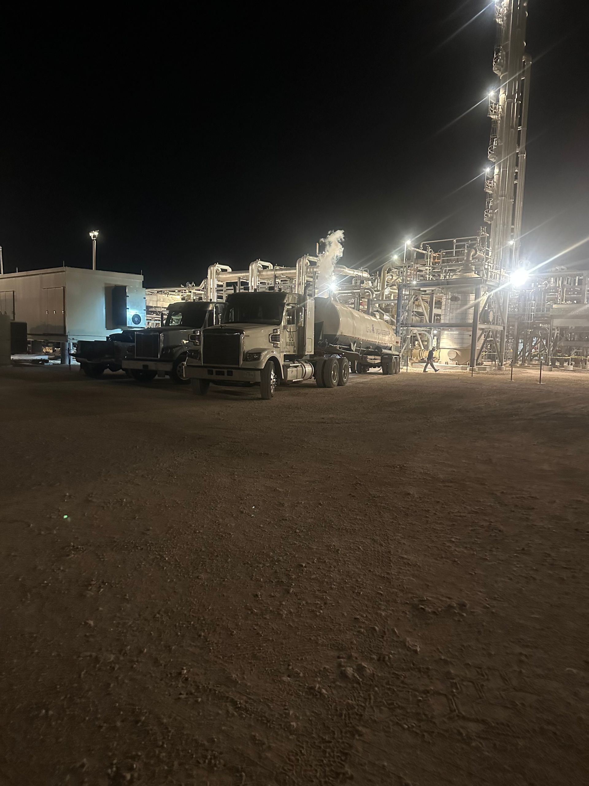 A lot of trucks are parked in a parking lot at night