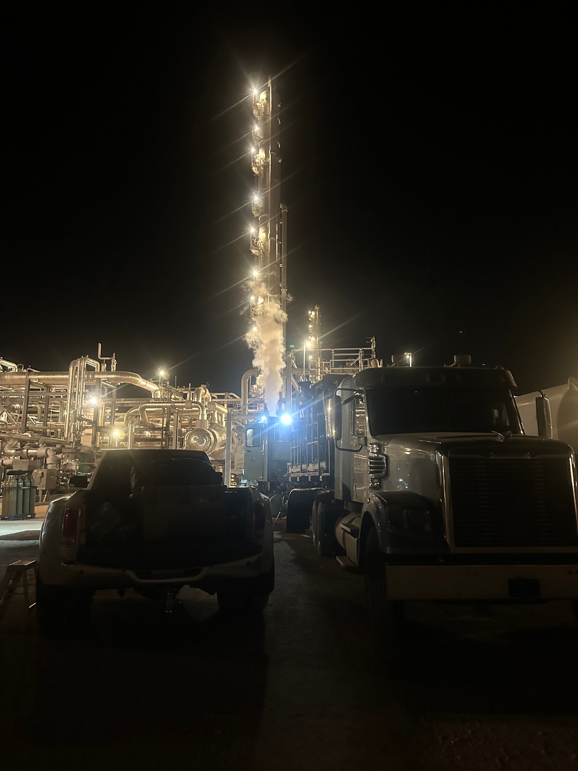 A truck is parked in front of a large building at night.
