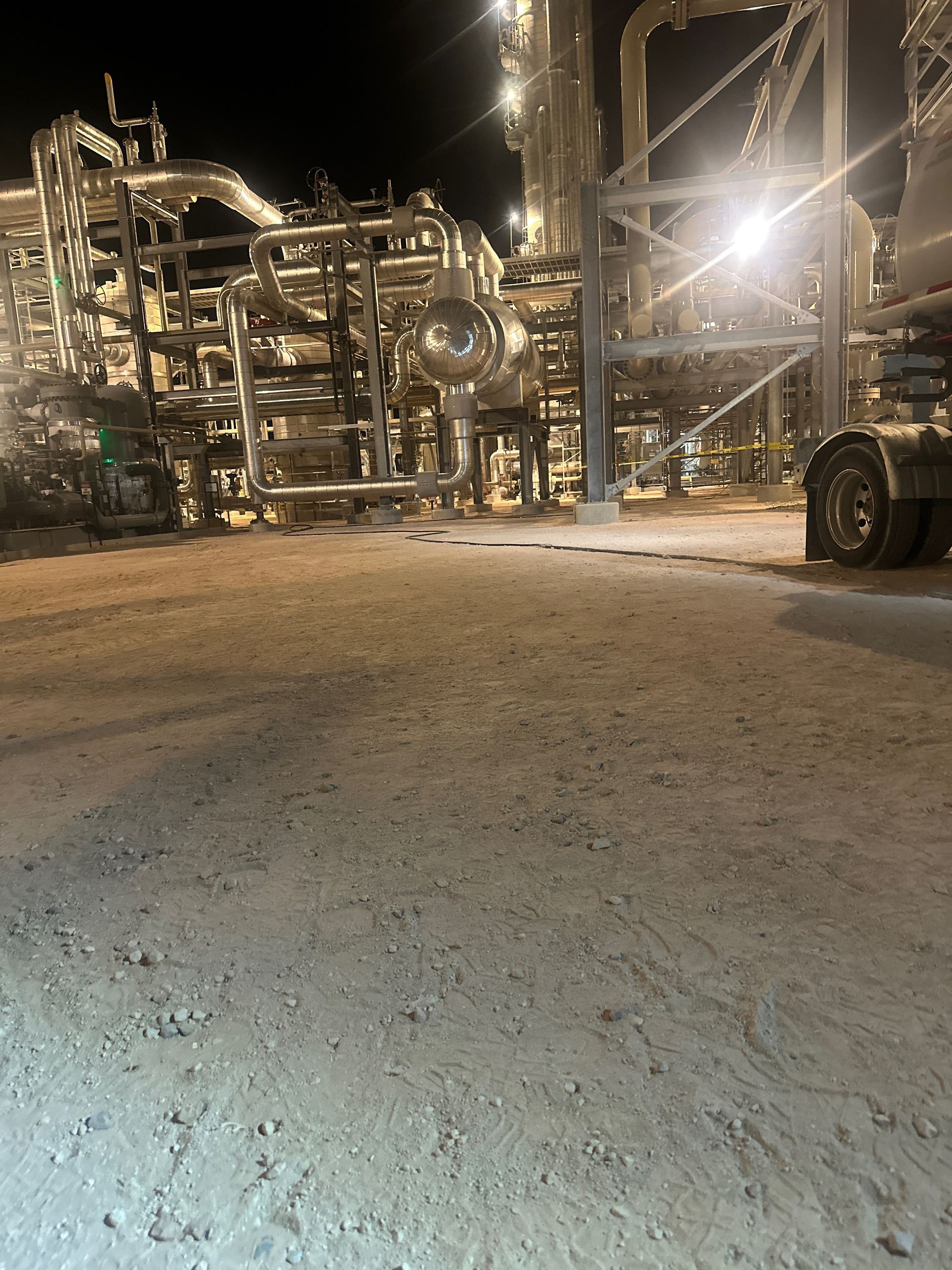 A truck is parked in front of a factory at night